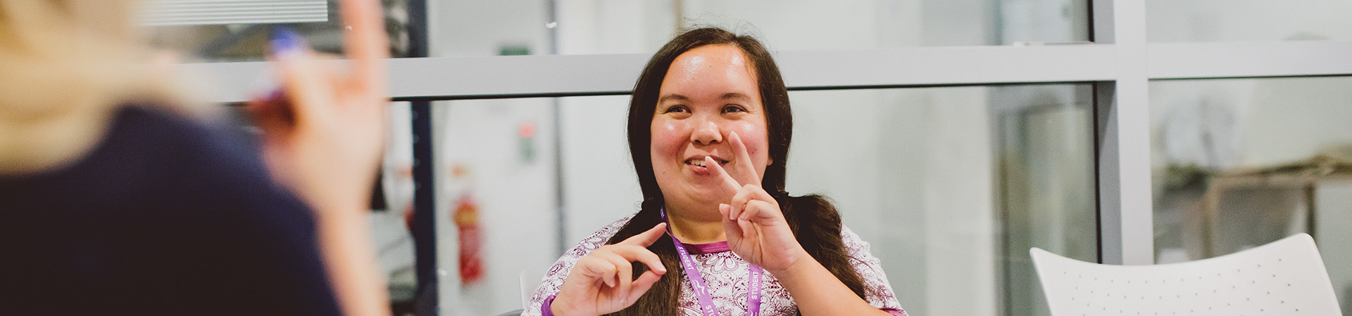 Student smiling and using sign language